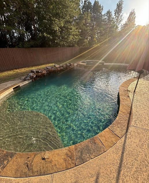 Freeform pool with rock waterfall at sunset